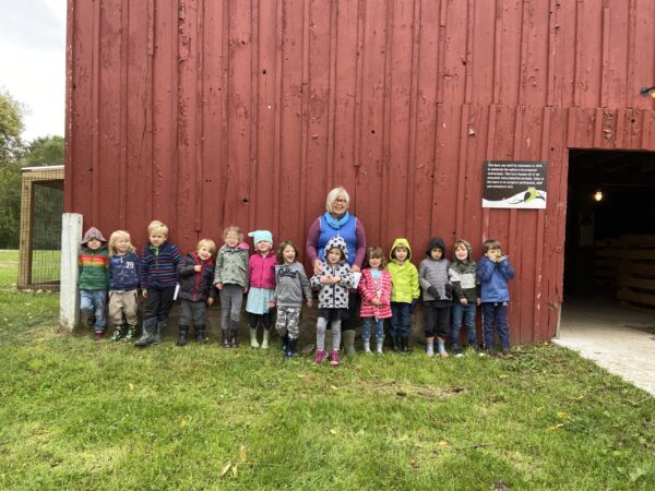 Mrs. Wilson and students by red barn wall